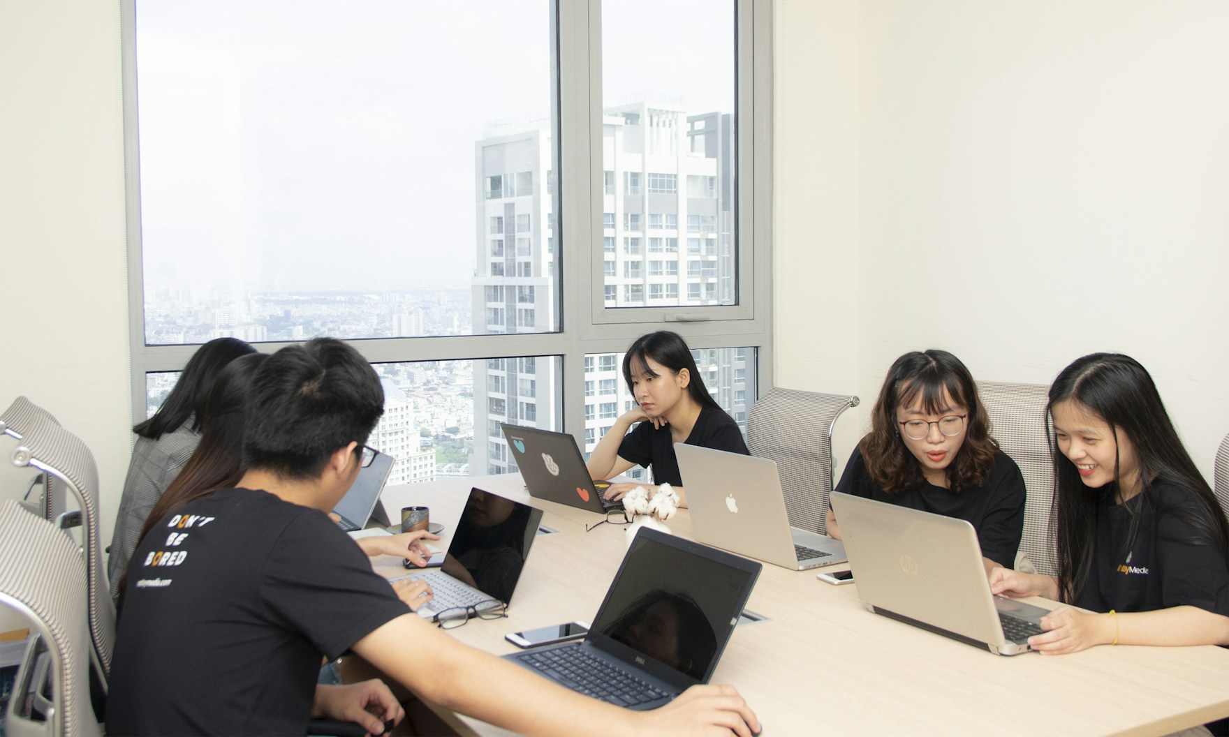 亚洲企业培训场景：团队在会议室围桌使用电脑协作学习